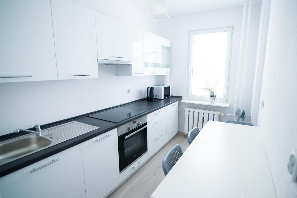 斯塔洛瓦沃拉Apartament pracowniczy的厨房配有白色橱柜、桌子和水槽。