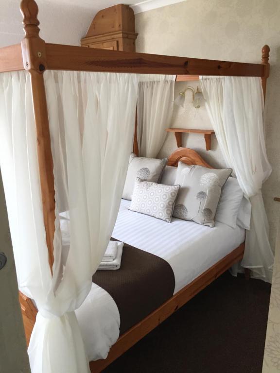斯凯格内斯Woodthorpe Hotel的卧室配有带白色窗帘的天蓬床
