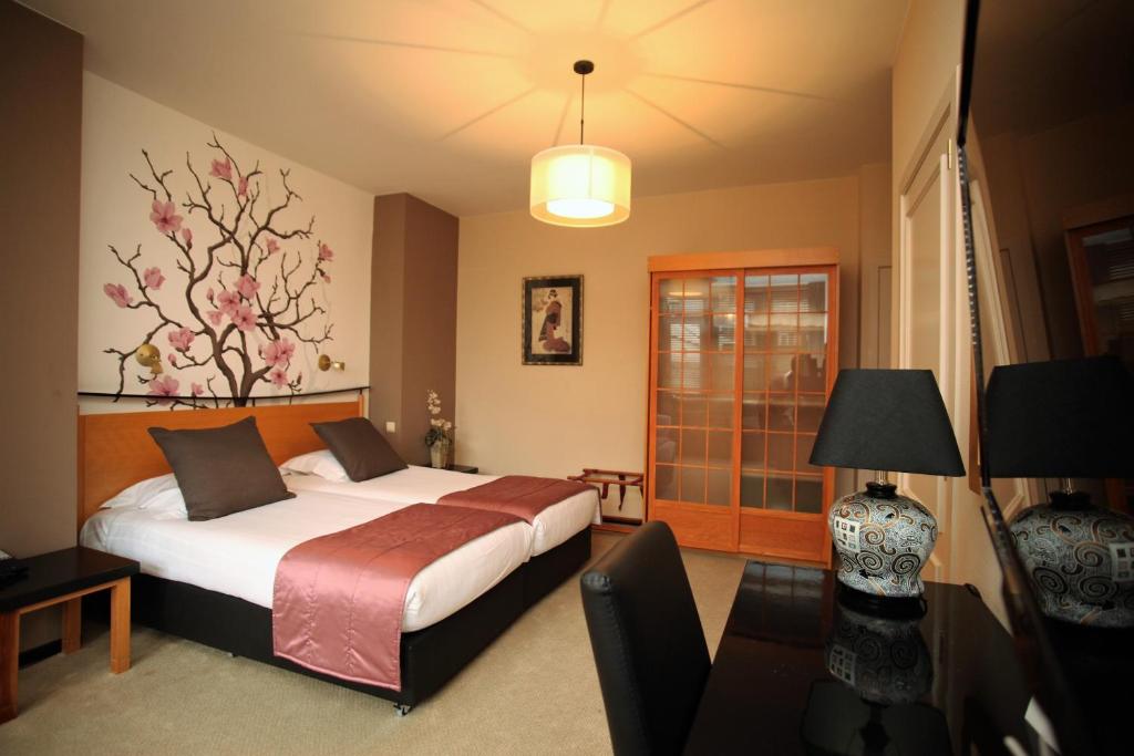 Wemmel玫瑰园酒店的一间卧室配有一张床和一张带台灯的桌子