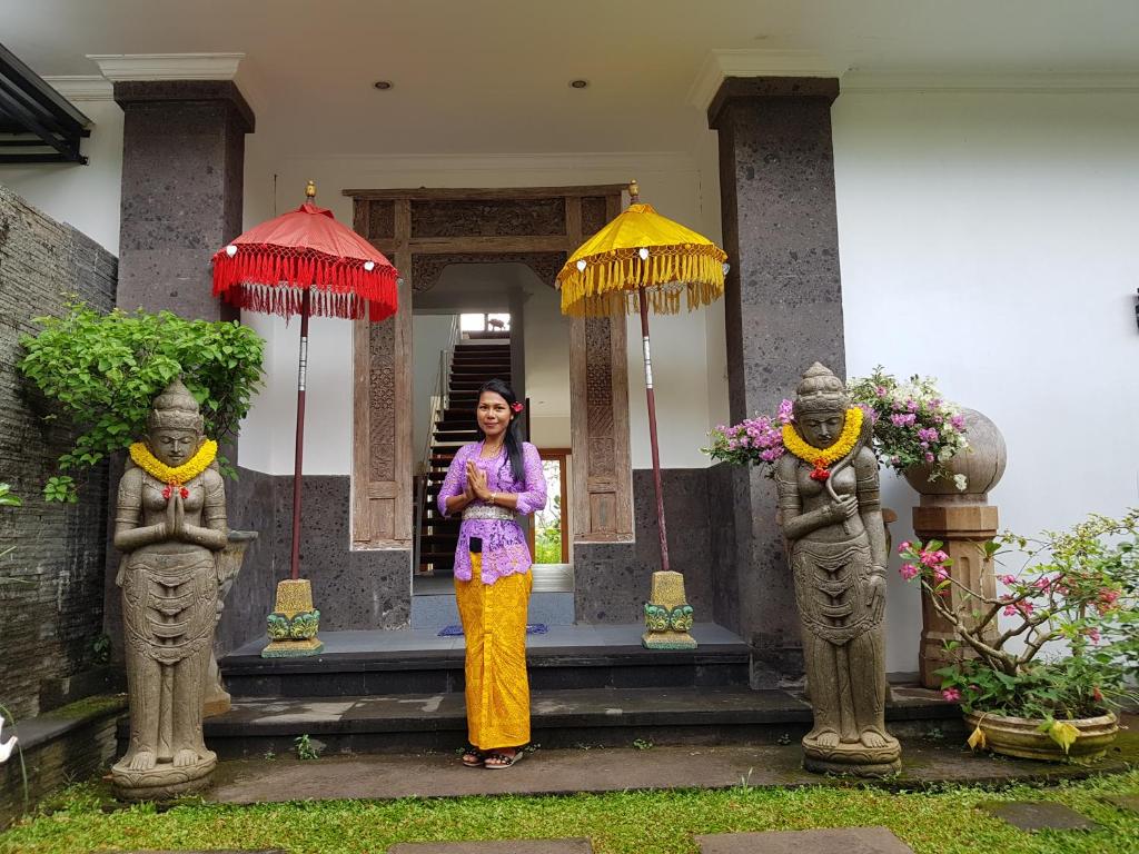 Tirtagangga三泰卡朗阿森别墅旅馆的站在一座有伞的建筑前面的女人