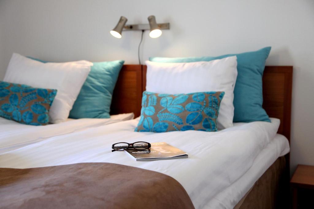 卡尔斯克鲁纳Hotell Conrad的床上一双眼镜,床上有蓝色枕头