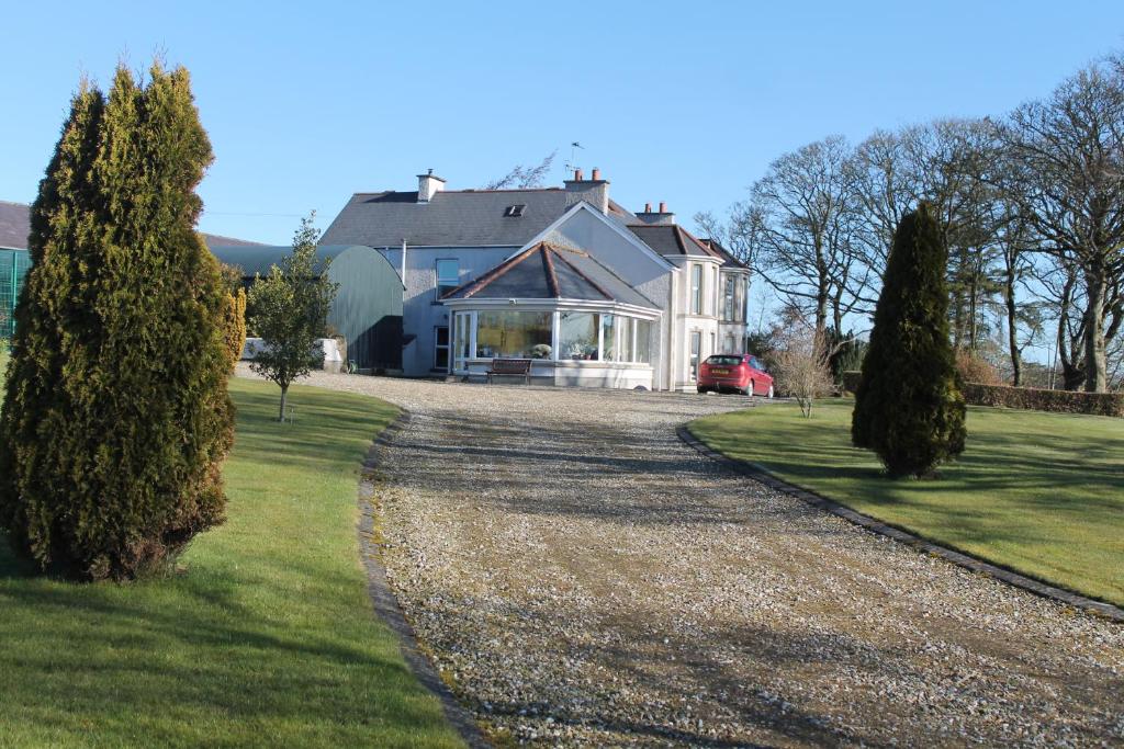 邓吉文Ballyhargan Farm House的一座带砾石车道的大型白色房屋