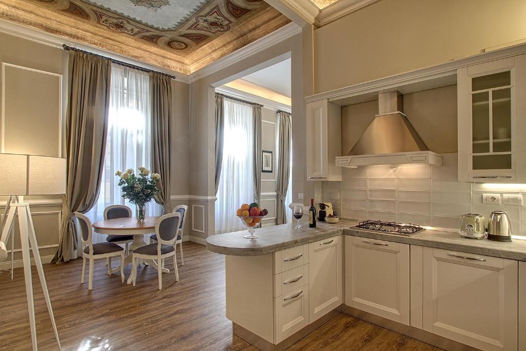 佛罗伦萨Art Apartment Luxury Family suite的厨房配有白色橱柜、桌子和用餐室。