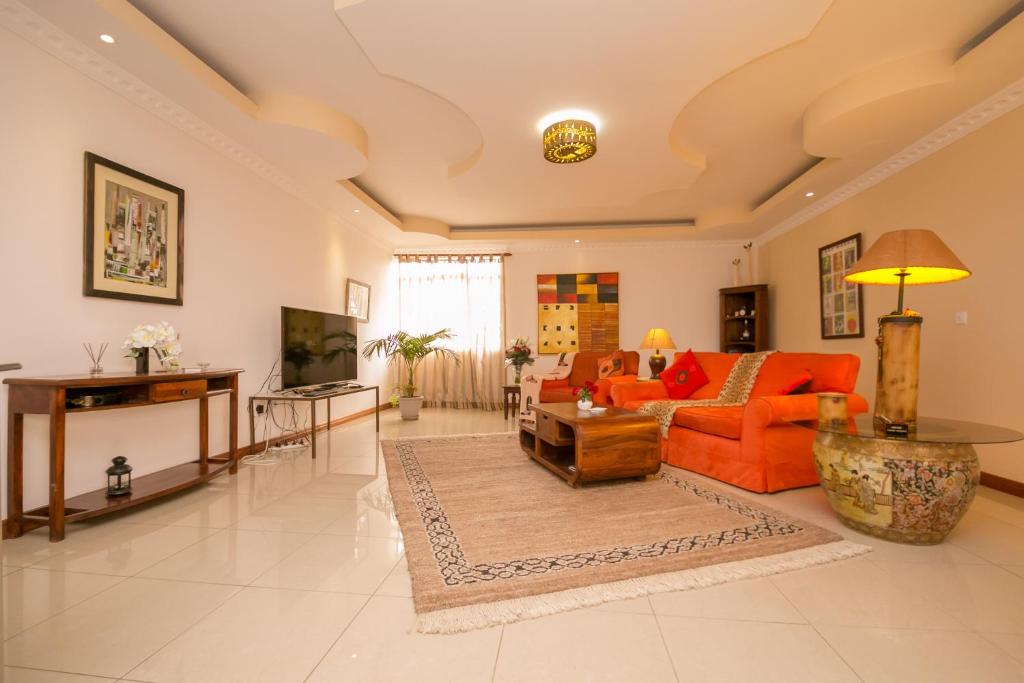 内罗毕Hotel Rudi的客厅配有橙色沙发和桌子