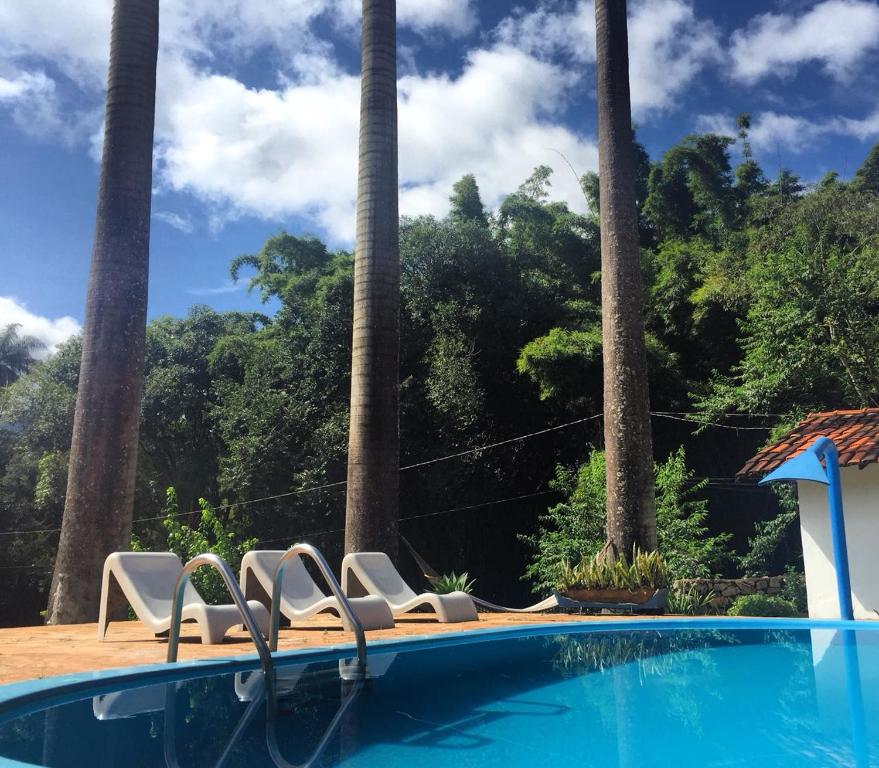 布鲁马迪纽Pousada Cantinho do Mundo的一个带两把椅子的游泳池,棕榈树