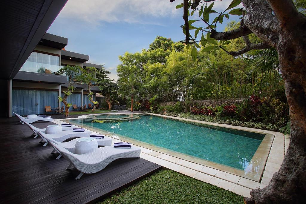 金巴兰Del Cielo Villa Jimbaran的一座房子旁带躺椅的游泳池