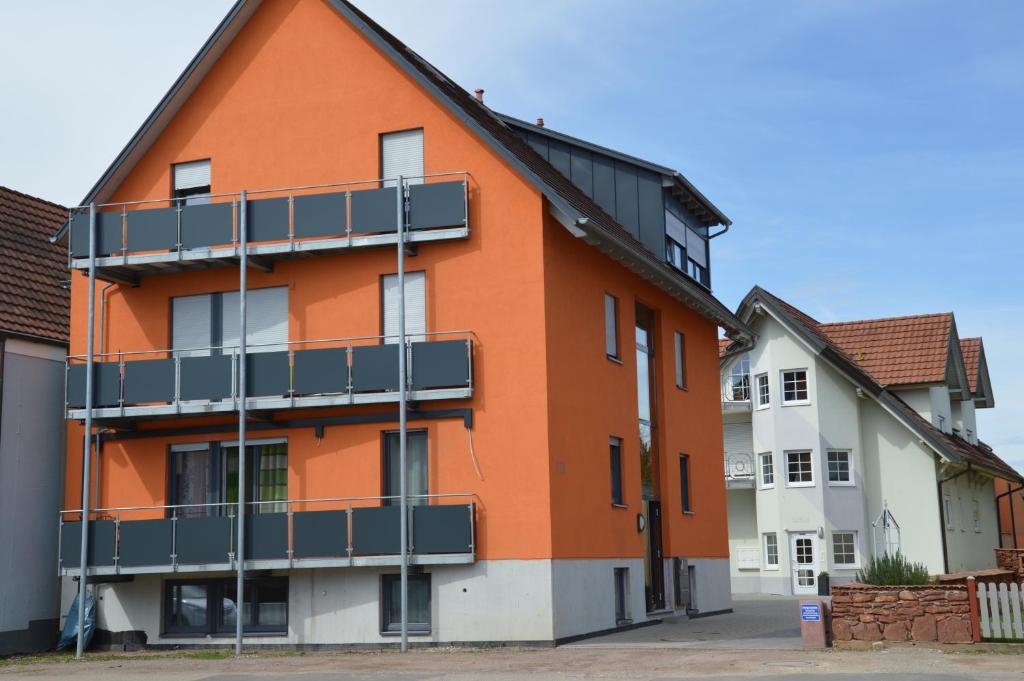 莱茵豪森Ferienwohnung Am Brunnen (Nähe Europapark)的一座橙色的建筑,旁边设有阳台