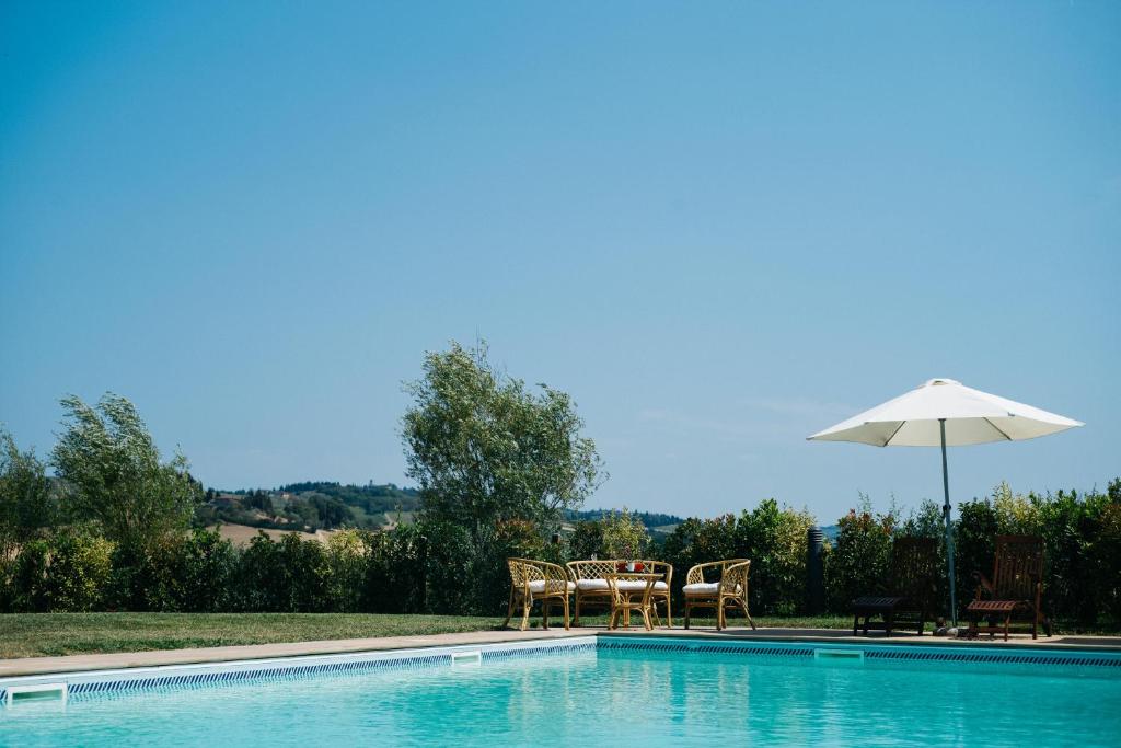 蒙泰斯佩尔托利Gatto Bianco Tizzauli的一个带桌子和遮阳伞的游泳池