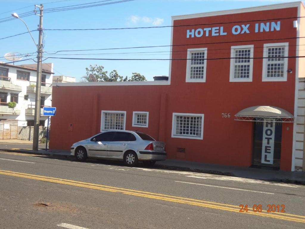 乌贝拉巴Hotel Ox Inn的停在红色建筑前面的汽车