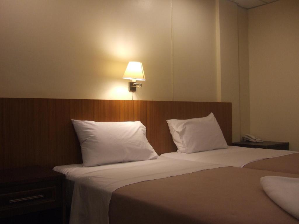 曼谷大堂吧61号酒店的一间卧室配有两张床、白色枕头和灯
