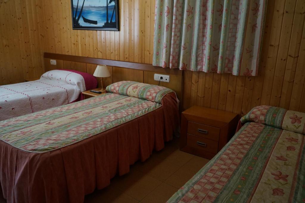 Calzadilla de la CuezaHostal Camino Real的客房设有两张床和一张带台灯的桌子。