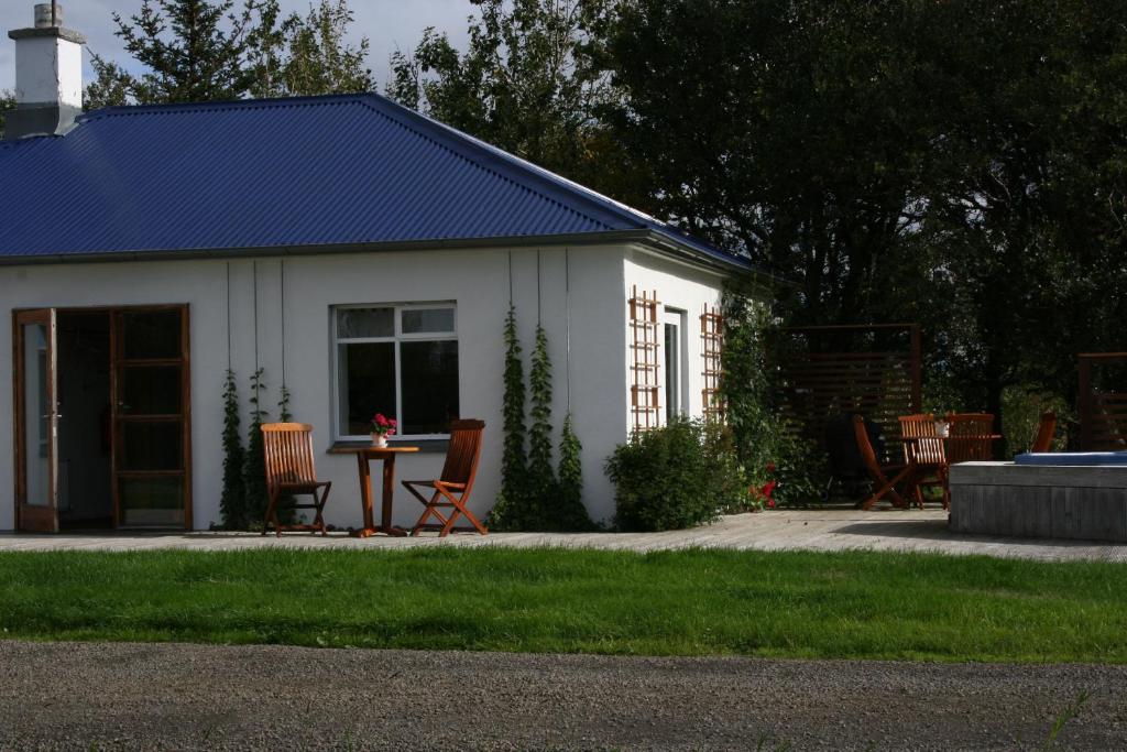BærJadar Farm的一座白色的建筑,在院子里设有椅子和桌子