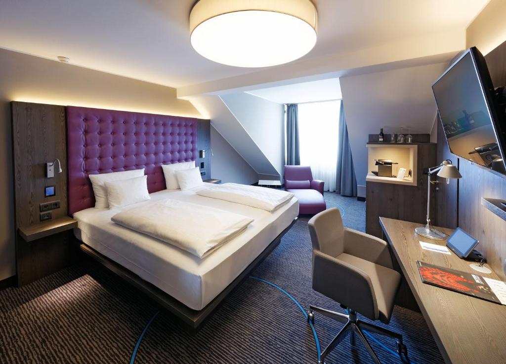 杜塞尔多夫慕尼黑斯塔迪特酒店的酒店客房设有一张大床和一张书桌。