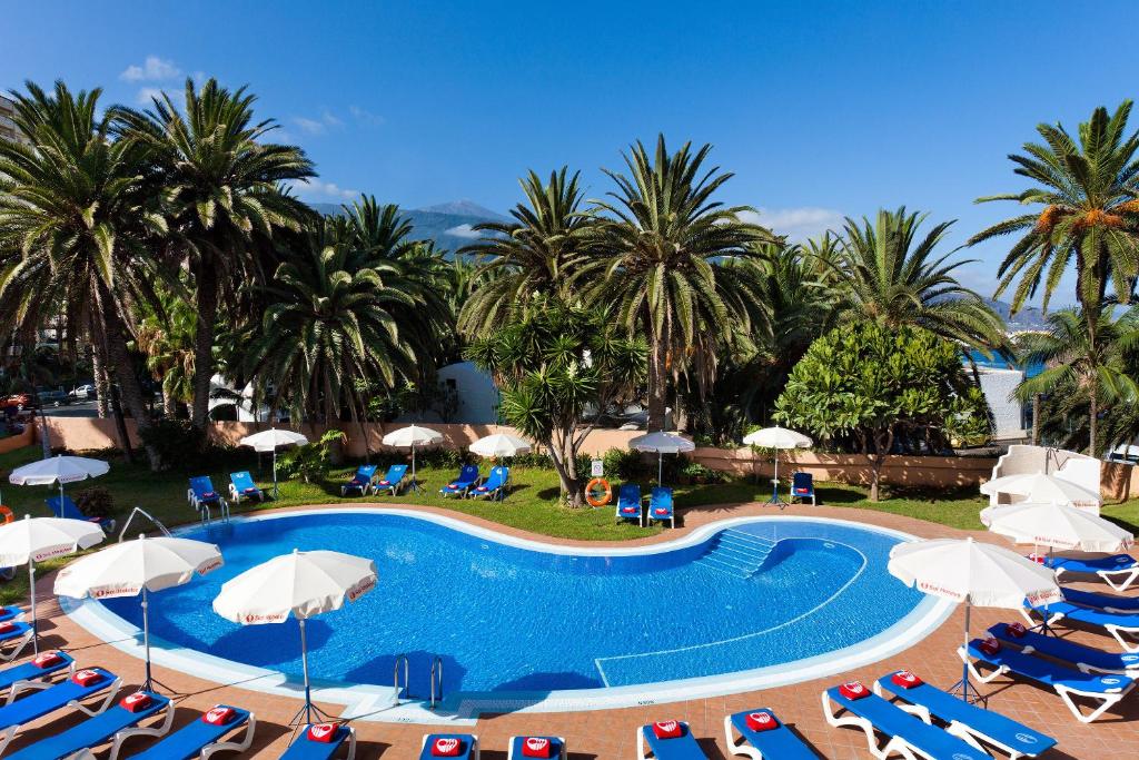 拉克鲁斯拉克鲁斯港特内里费阳光酒店的一个带椅子和遮阳伞的游泳池以及棕榈树