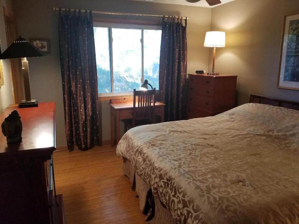 金斯顿Beautiful Views on Golf Course的一间卧室配有一张床、一张书桌和一个窗户。