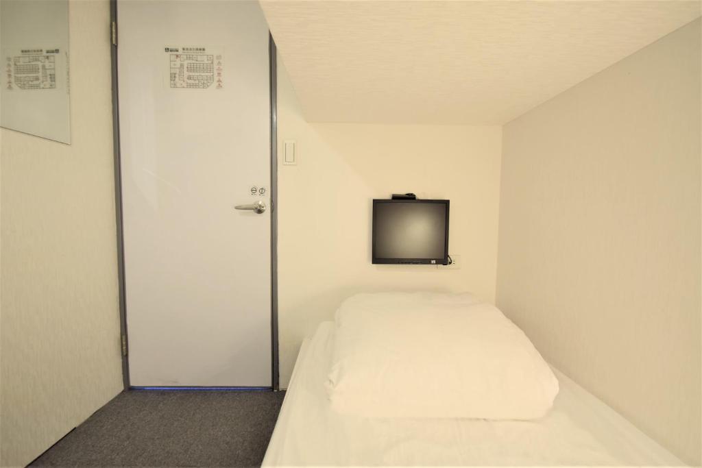台北品格子旅店北车馆的小房间设有一张床和墙上的电视