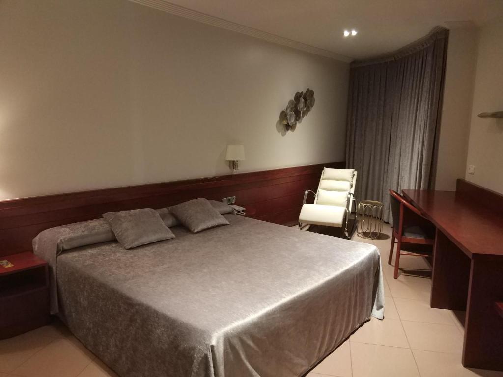 曼雷沙Hotel Els Noguers的一间卧室配有一张床、一张桌子和一把椅子