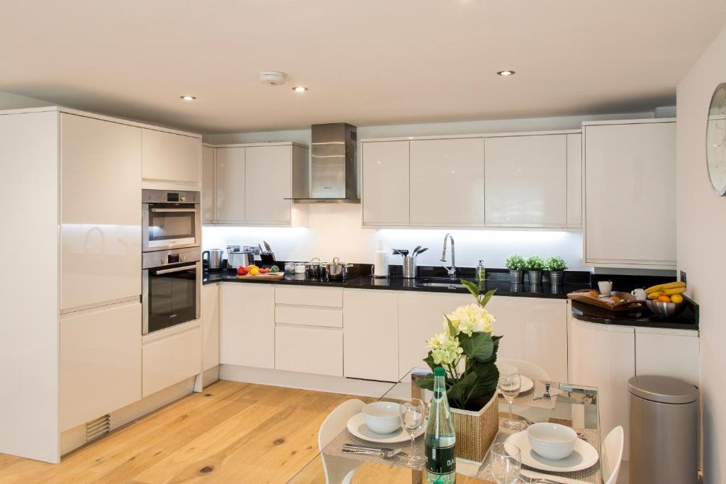 亨顿Finchley Central - Luxury 2 bed ground floor apartment的厨房配有白色橱柜和玻璃桌