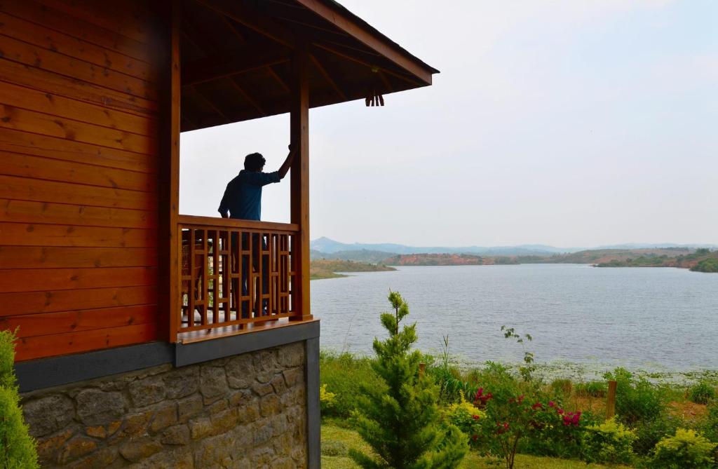 安巴拉瓦亚尔LakeRose Wayanad Resort的站在建筑的阳台上,享有水景的人