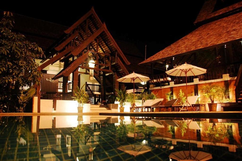 清迈Rainforest ChiangMai Hotel的一个带桌子和遮阳伞的游泳池的度假酒店