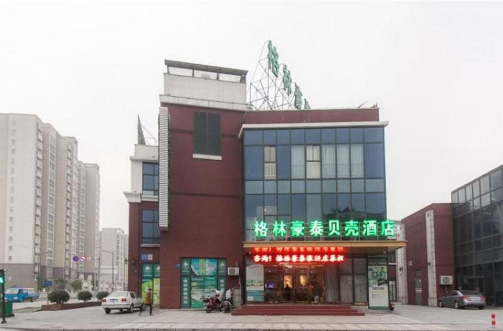 无锡格林豪泰江苏省无锡市锡北镇星天地贝壳酒店的城市中一座有 ⁇ 虹灯标志的建筑