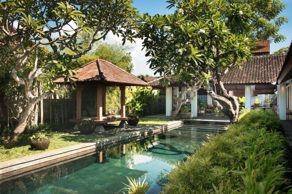 沙努尔Atelier TE Designer Guesthouse的一座树木繁茂的房屋前的游泳池