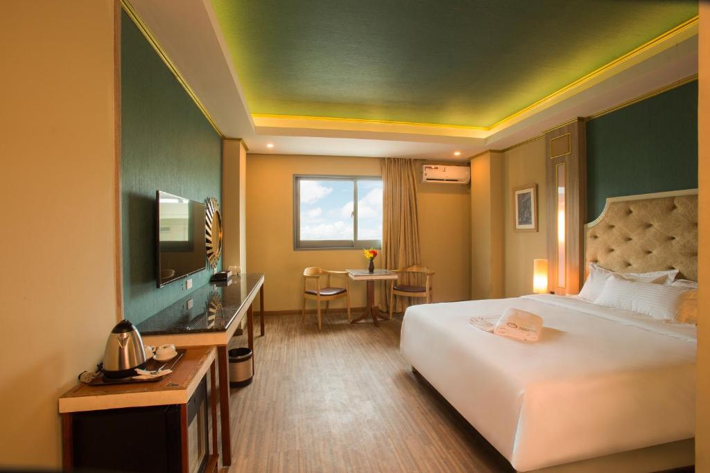 麦克坦Appleton Boutique Hotel Mactan Cebu的酒店客房配有一张床、一张书桌和一台电视。