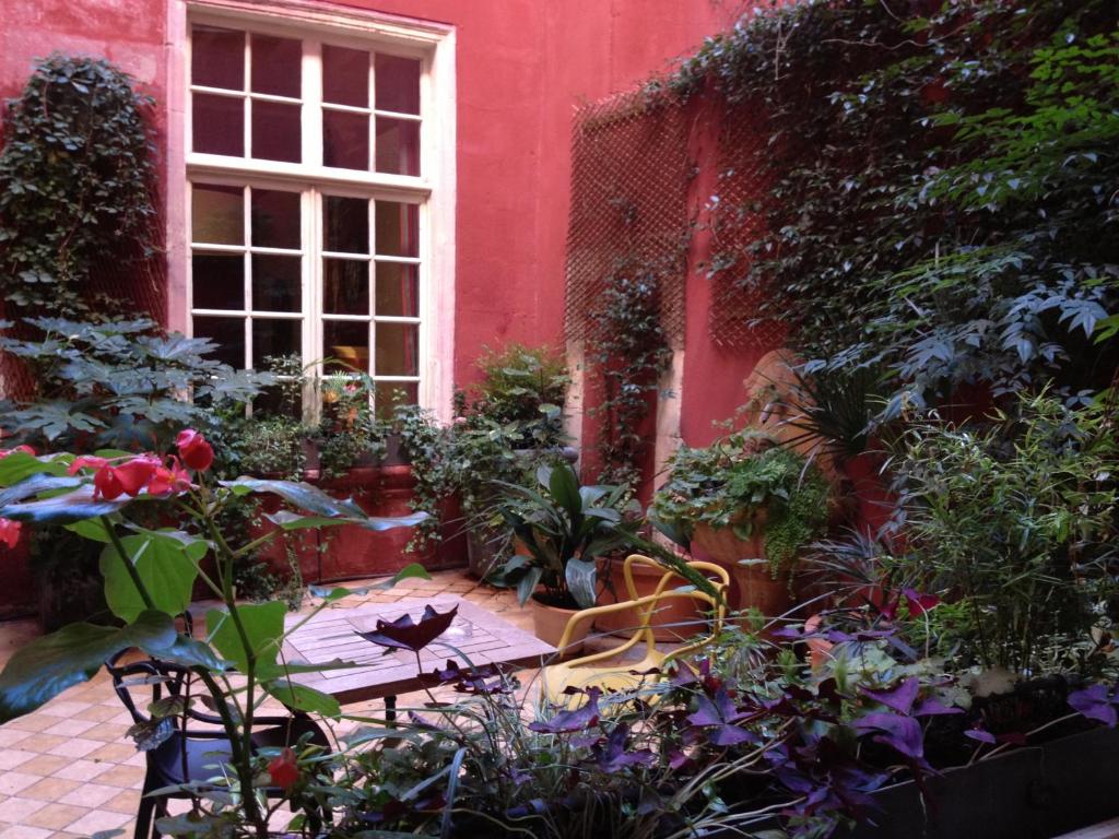 阿尔勒露天剧场酒店的一座红色建筑前的花园,花园内摆放着桌子和鲜花