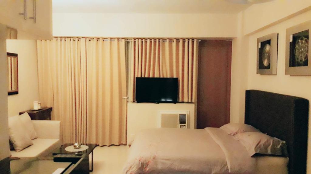 马尼拉棕榈树别墅1号公寓的一间卧室配有一张床、一张沙发和一台电视