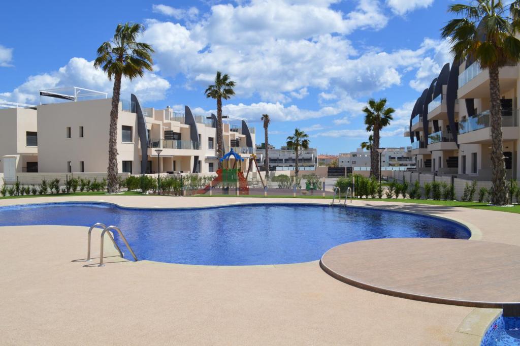 皮拉尔－德拉奥拉达达Apartment Playa Elisa Bay的大楼前带游乐场的游泳池