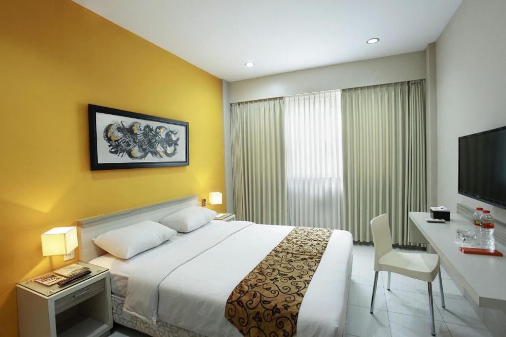 日惹瑞维莎酒店的一间卧室配有一张床、一张书桌和一台电视