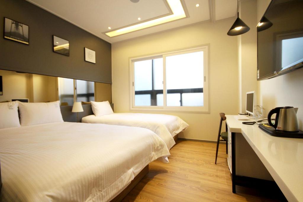 昌原市If Business Hotel的酒店客房设有两张床和窗户。