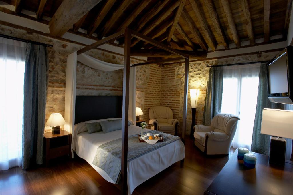 Los Santos de la Humosa罗马教皇酒店的一间卧室配有一张天蓬床和一把椅子