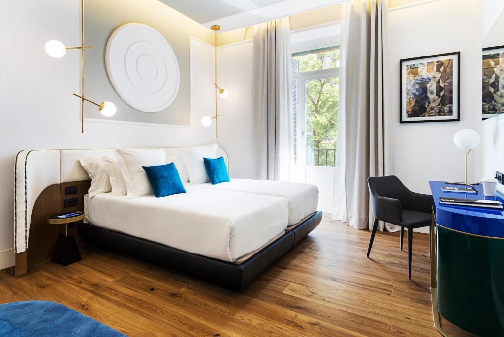 马德里万夏特福尔图尼07酒店的配有蓝色枕头的床的酒店客房