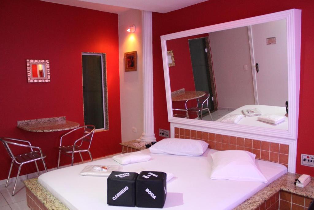 瓜鲁柳斯Motel Emoções de Guarulhos的红色的房间,配有一张带镜子的床