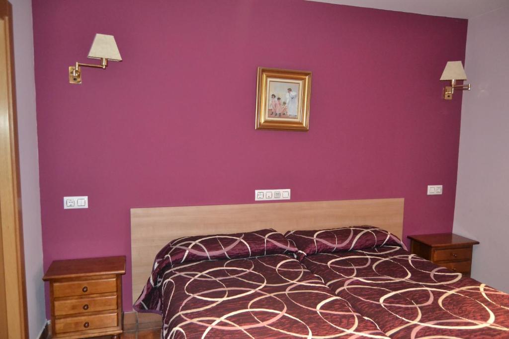 索里亚阿勒瓦科斯旅馆的一间卧室配有一张紫色墙壁和床