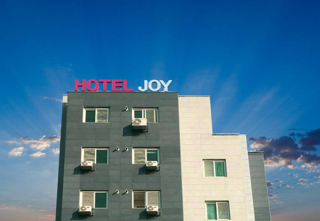 平泽市Hotel Joy near Camp Humphres的上面有酒店欢乐标志的建筑