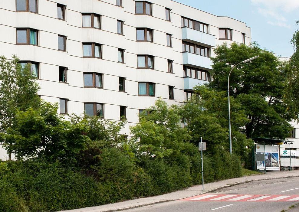 因河畔布劳瑙SOVEA Hotel - Braunau的一条街道前方树木繁茂的大型白色建筑