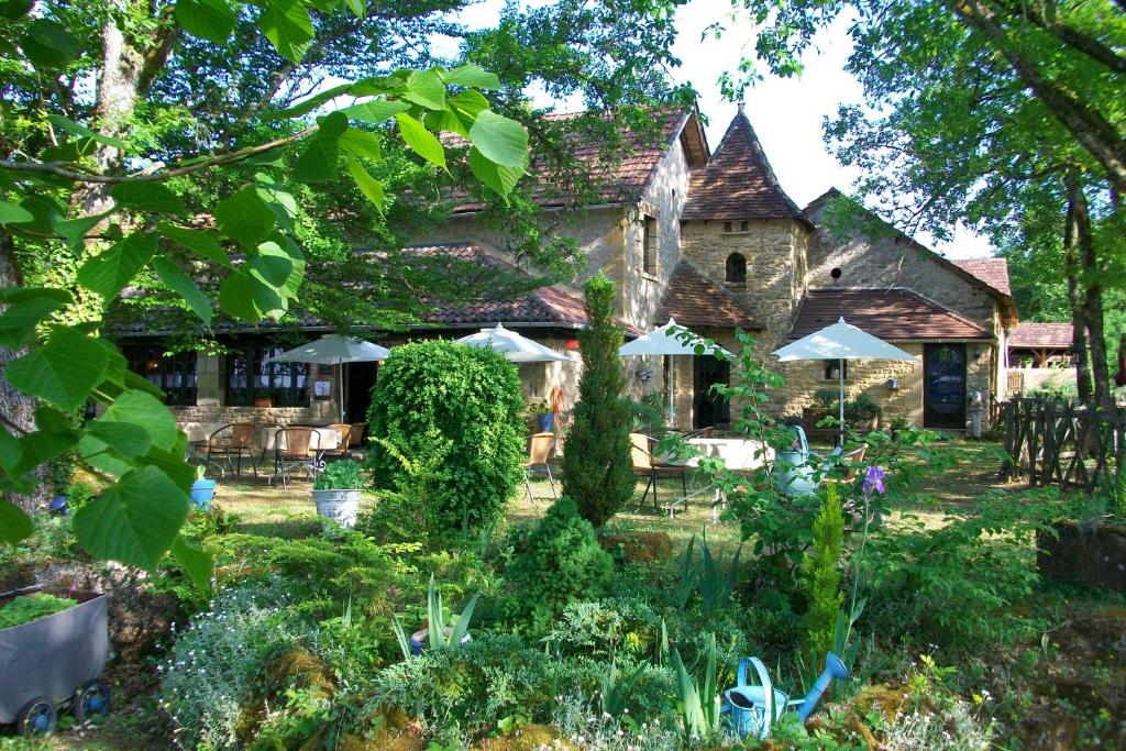 SergeacAuberge de Castel-Merle的一座花园,位于一座带遮阳伞的房子前