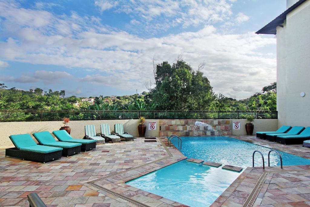 马盖特Uvongo River Resort的游泳池旁的游泳池配有蓝色躺椅