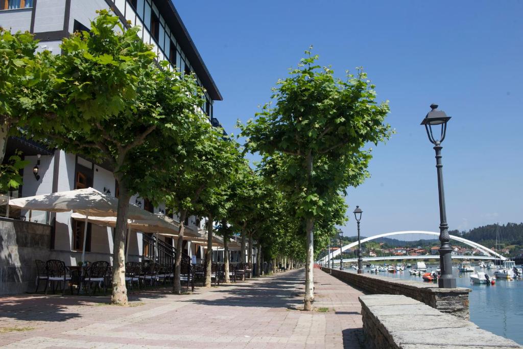 普伦西亚Hotel Boutique Bahía de Plentzia的运河边一条树木林立的街道