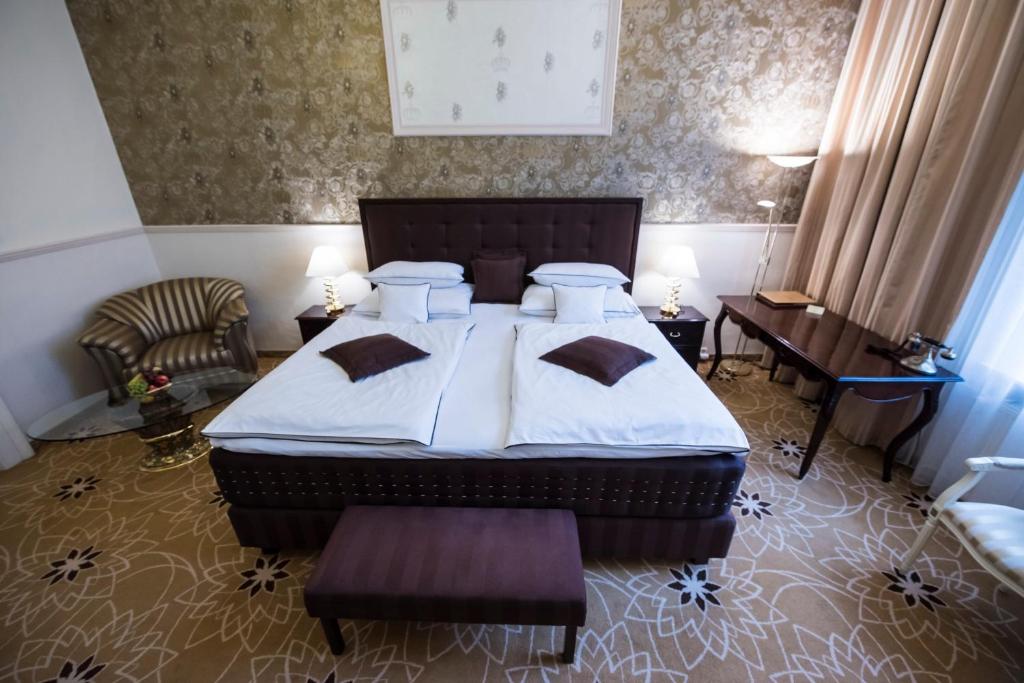 科希策金色皇家精品酒店 & 温泉中心的一间卧室配有一张床、一把椅子和一张桌子