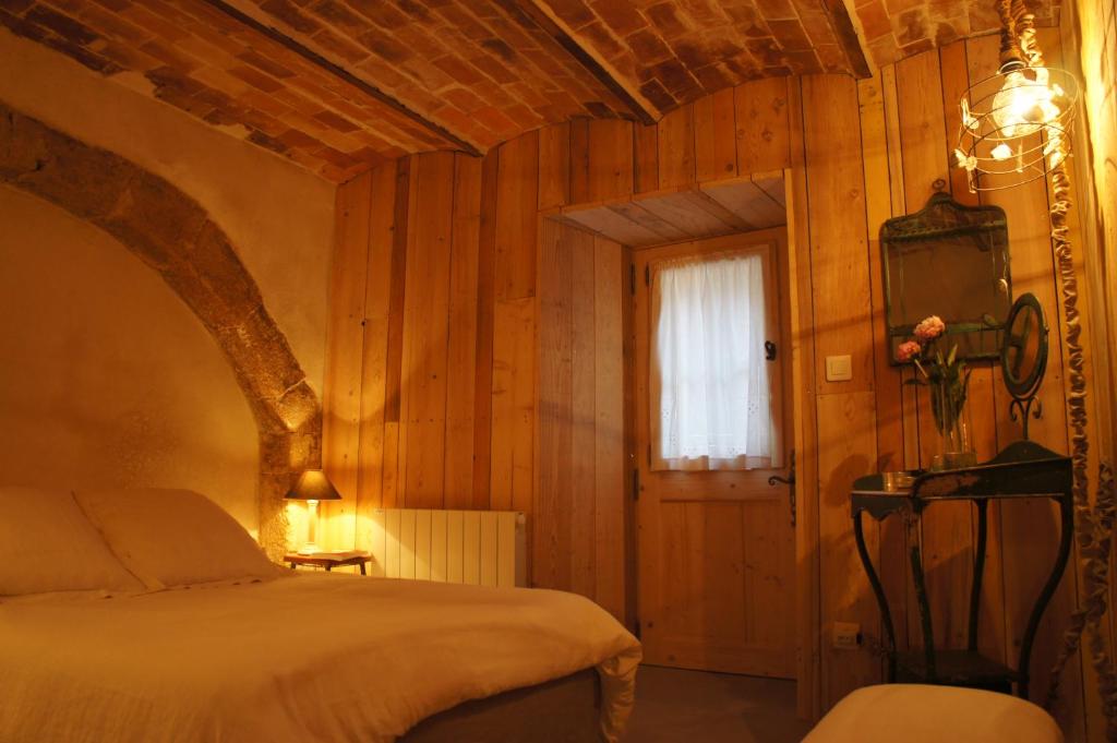 卢马罕la chambre d'hôte的卧室配有一张床铺,位于带木墙的房间内