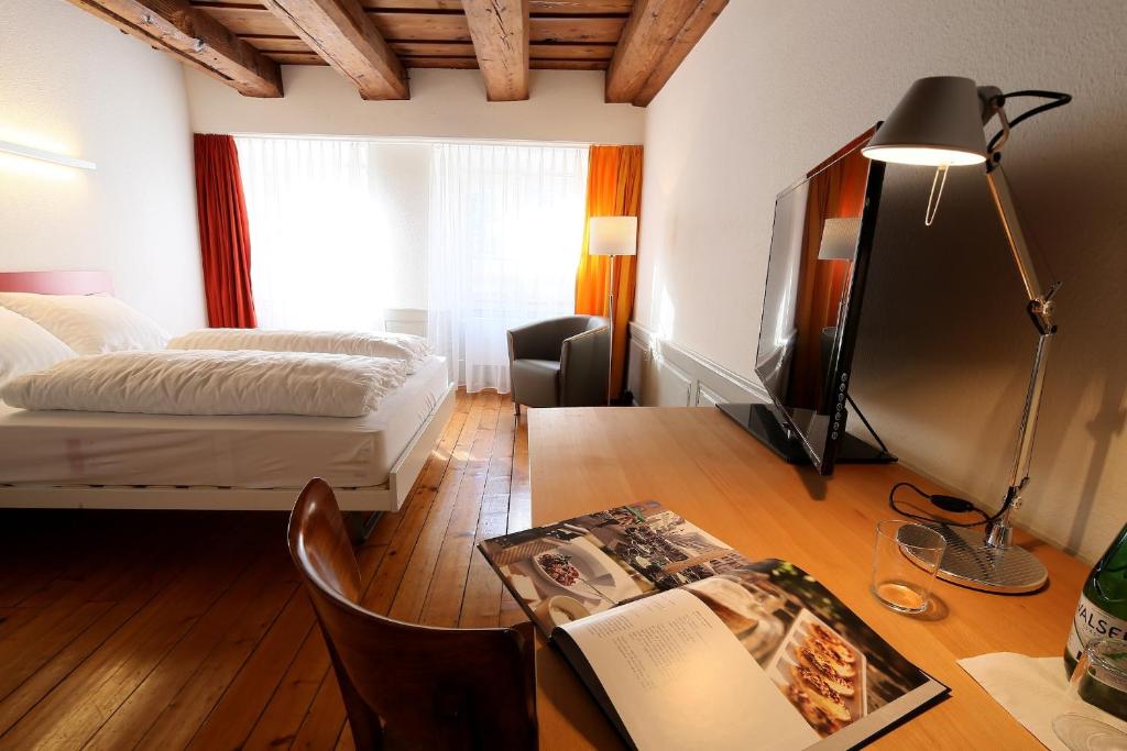 索洛图恩罗特尔奥克森酒店的一间卧室配有一张床和一张写有书籍的书桌