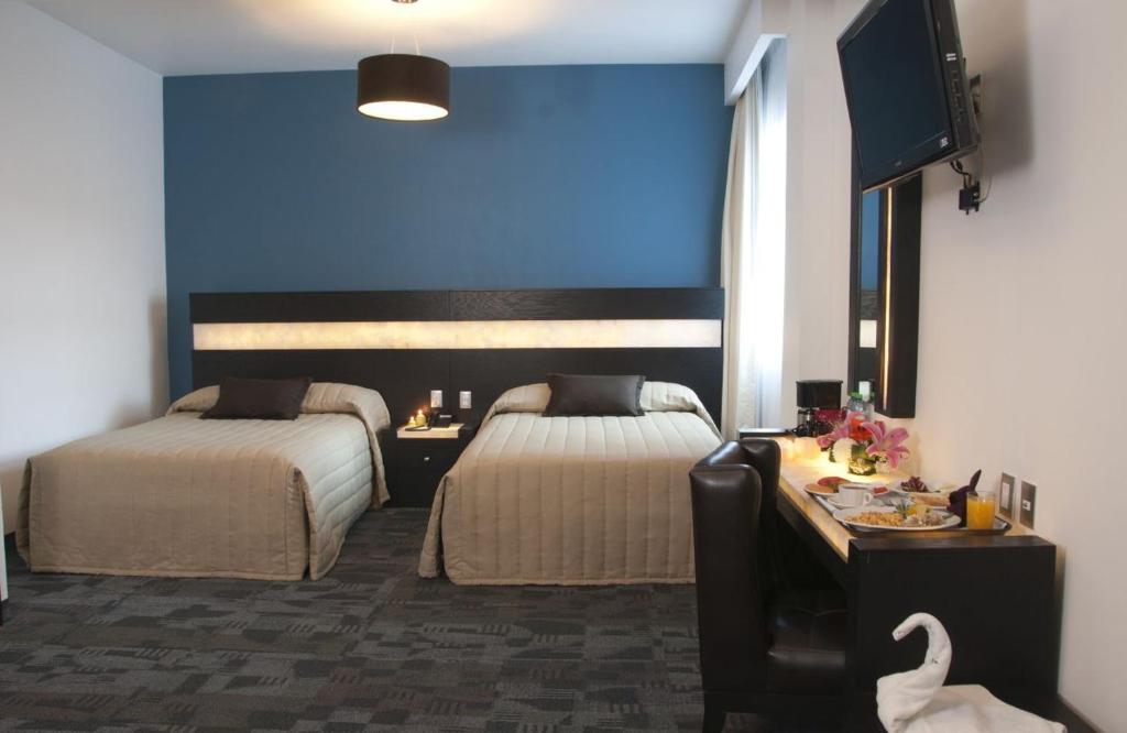 莱昂Hotel Real Rex的酒店客房设有两张床和蓝色的墙壁。
