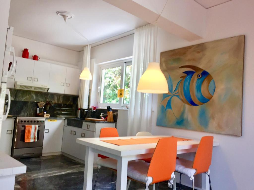 马蒂Flower Garden的厨房配有白色的桌子和橙色的椅子