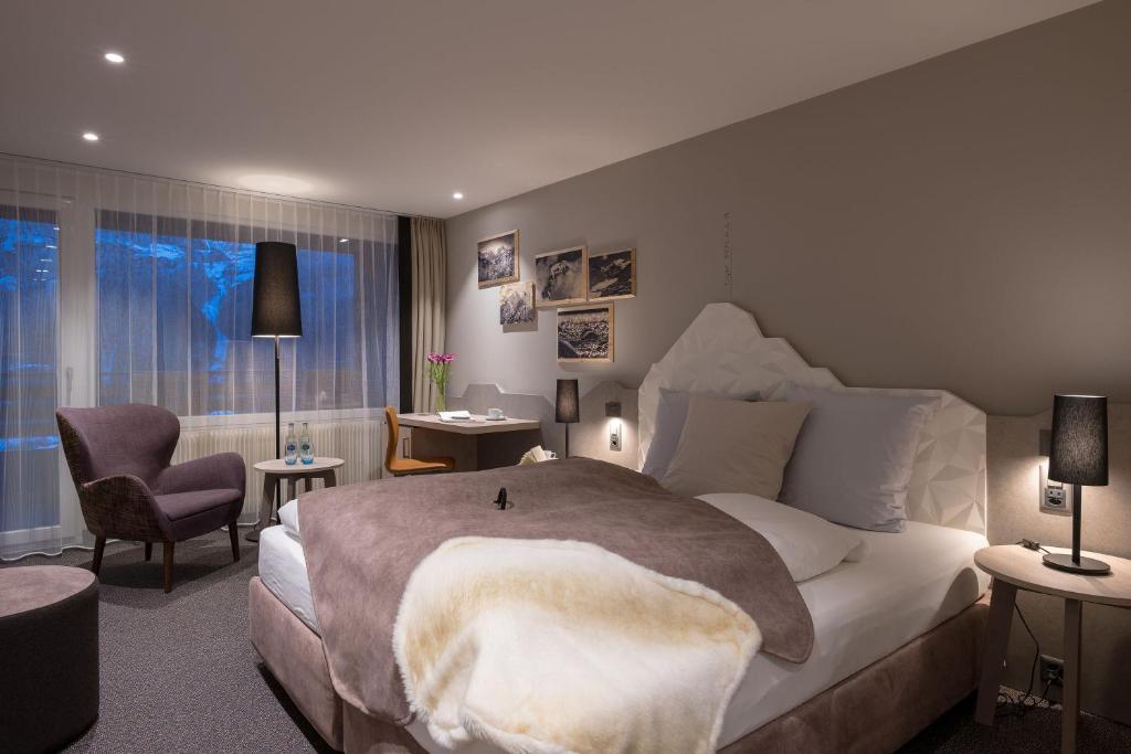 格林德尔瓦尔德格林德尔瓦尔德阳光星辰酒店的一间卧室配有一张大床和一把椅子