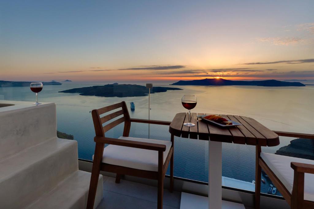 费拉Iriana Suites的阳台上的桌子和两杯葡萄酒