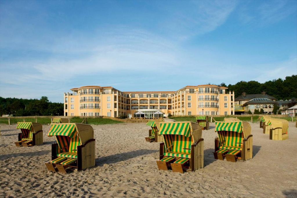 沙博伊茨Hotel Gran BelVeder & Ostsee Therme Resort & Spa的大楼前海滩上的一组椅子