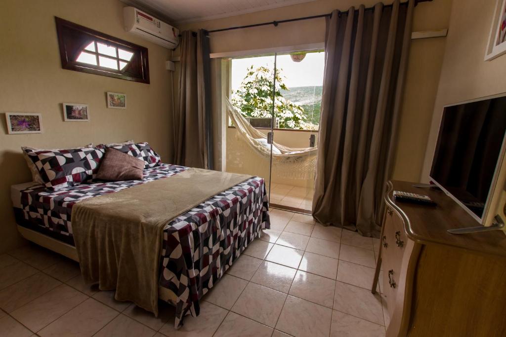 伦索伊斯Pôr do Sol Suítes的一间卧室设有一张床、一台电视和一个窗口。